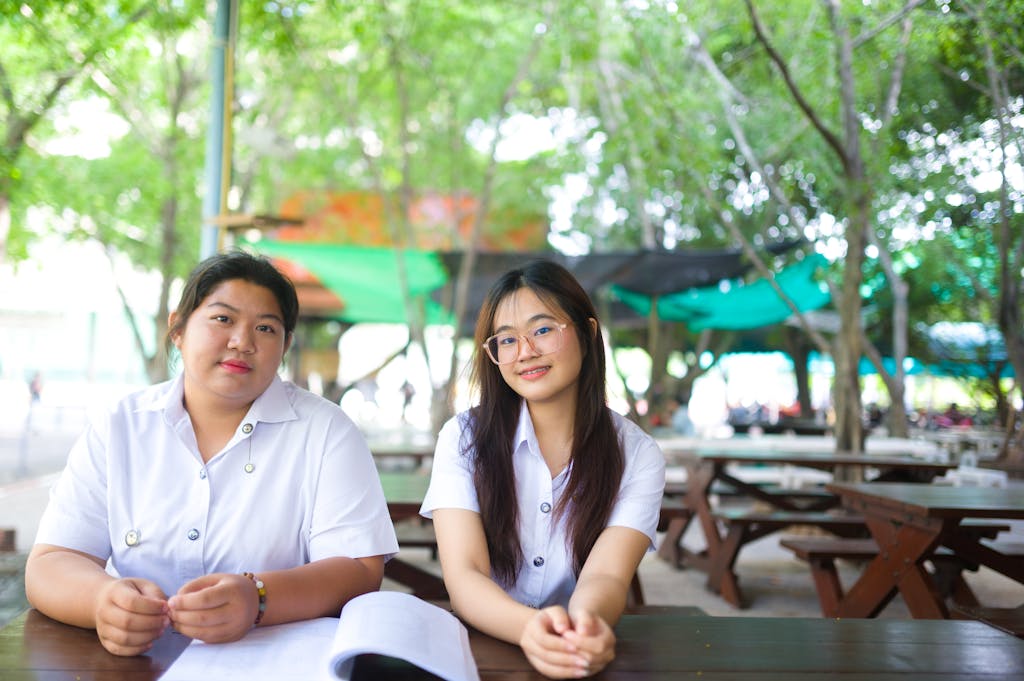 Two women sitting at a table in a park, enjoying a relaxing day outdoors.